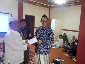 Ketua Panitia MTQ XIV PW JQH Jawa Timur, Musyafa' Aly saat menyerahkan surat resmi kepada KH Mun'im Syadzili, Pengasuh Ponpes Asy-Syadzili, Pakis Malang